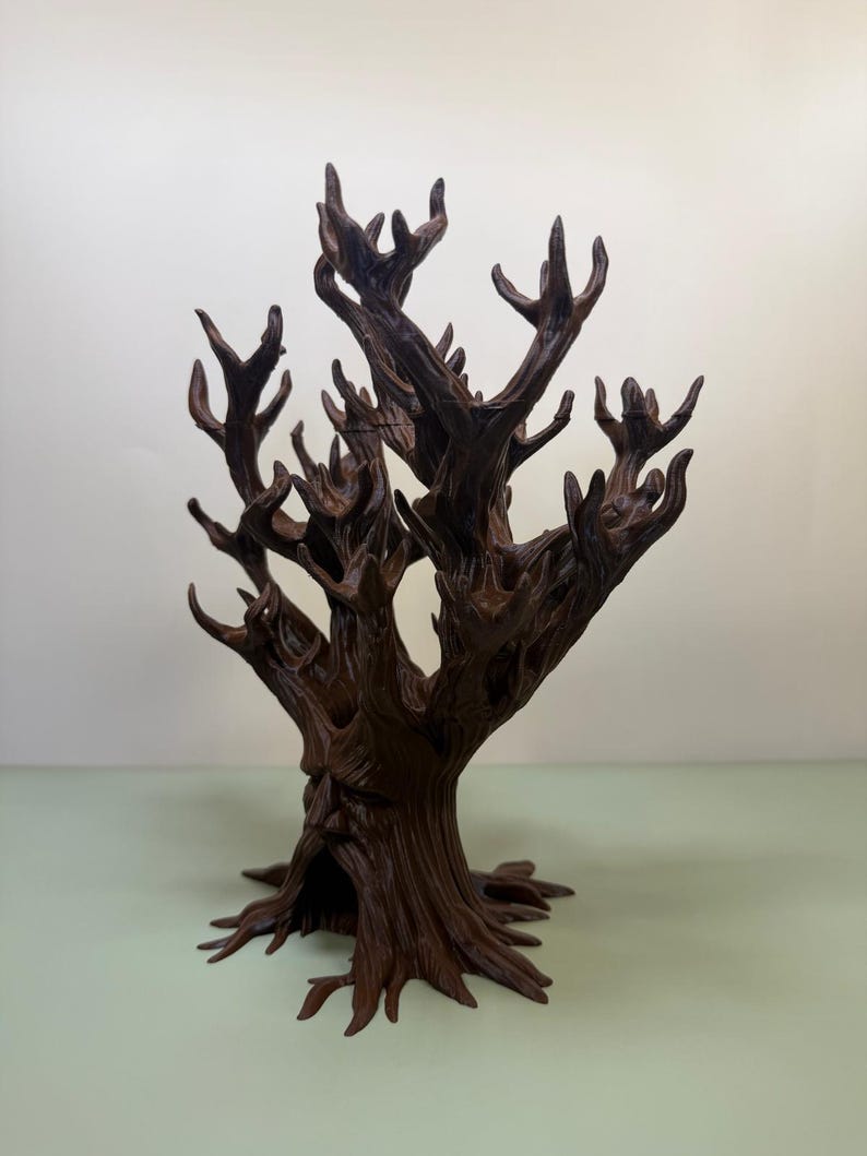 Pu&ograve; includere: Una scultura di albero marrone scuro stilizzata con un volto scolpito nel tronco. L'albero ha molti rami e una superficie strutturata dettagliata. La scultura &egrave; un oggetto decorativo.