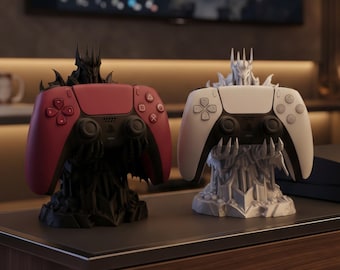 Könnte beinhalten: Zwei Gaming-Controller-Ständer in Form von gepanzerten Figuren mit gezackten Kronen. Ein mattschwarzer Ständer hält einen roten Controller, der andere in Mattweiß hält einen weißen Controller. Beide Ständer haben krallenartige Hände als Halterung.