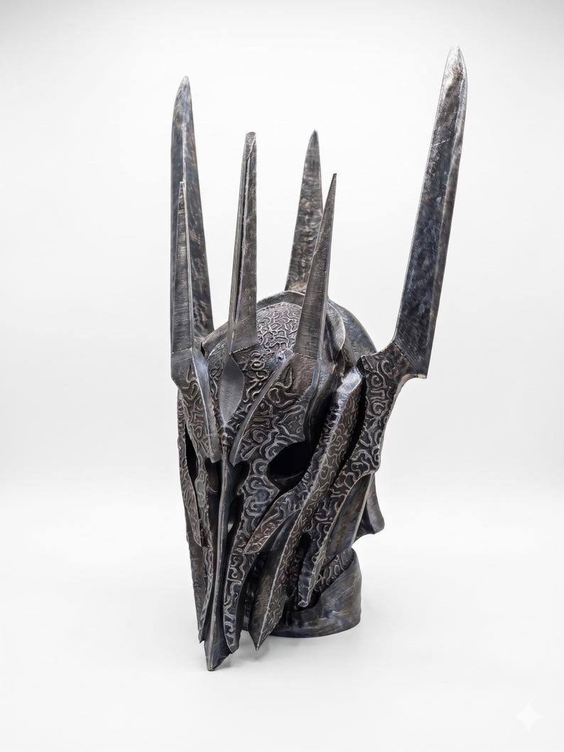 K&ouml;nnte beinhalten: Ein dunkler Metallhelm mit einer hohen, spitzen Krone und mehreren vertikalen Zacken. Die Oberfl&auml;che ist mit komplizierten, erhabenen Schn&ouml;rkelmustern bedeckt und hat ein verwittertes, gunmetallgraues Finish mit tiefen Schatten.