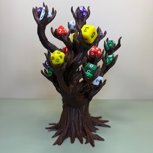 Pu&ograve; includere: Un porta dadi a forma di albero marrone con pi&ugrave; rami, ognuno dei quali contiene un colorato set di dadi poliedrici. I dadi sono di vari colori, tra cui giallo, verde, rosso e viola. Il supporto &egrave; progettato per esporre e conservare i dadi.