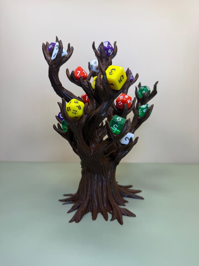 Pu&ograve; includere: Un porta dadi a forma di albero marrone con pi&ugrave; rami, ognuno dei quali contiene un colorato set di dadi poliedrici. I dadi sono di vari colori, tra cui giallo, verde, rosso e viola. Il supporto &egrave; progettato per esporre e conservare i dadi.
