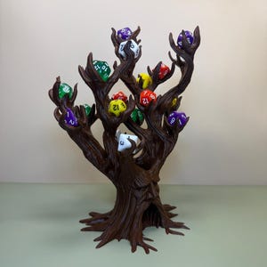 Pu&ograve; includere: Un porta dadi a forma di albero marrone, con pi&ugrave; rami, ognuno dei quali tiene un dado di colore diverso. I dadi sono di vari colori, tra cui verde, rosso, viola e giallo. Il supporto &egrave; progettato per assomigliare a un tronco e ai rami di un albero.
