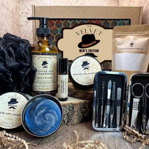 Puede incluir: Un set de regalo para hombres que incluye una caja marr&oacute;n con un patr&oacute;n de cuadros negros y rojos. La caja contiene una botella de vidrio transparente de gel de ducha, una peque&ntilde;a botella de manteca corporal, una barra de jab&oacute;n, una toallita negra, un juego de manicura plateado y una bolsa de sales de ba&ntilde;o. Los productos est&aacute;n etiquetados con el texto "The Velvet Men's Edition" y "Vetiver and Teakwood".