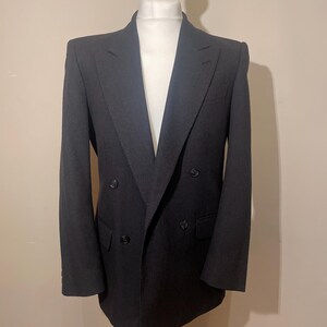 Op de afbeelding: Een donkergrijze dubbelrijdige blazer met een reverskraag en vier knopen.