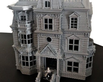 May include: A detailed, gray miniature Victorian house with multiple stories, dormers, and intricate architectural details. The house features a front porch with a small figure, and decorative trim along the roofline and windows. The overall design suggests a haunted house theme.