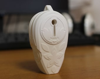 May include: White ceramic ornament with a floral design and a keyhole in the center. The ornament has a raised design of a flower and leaves.