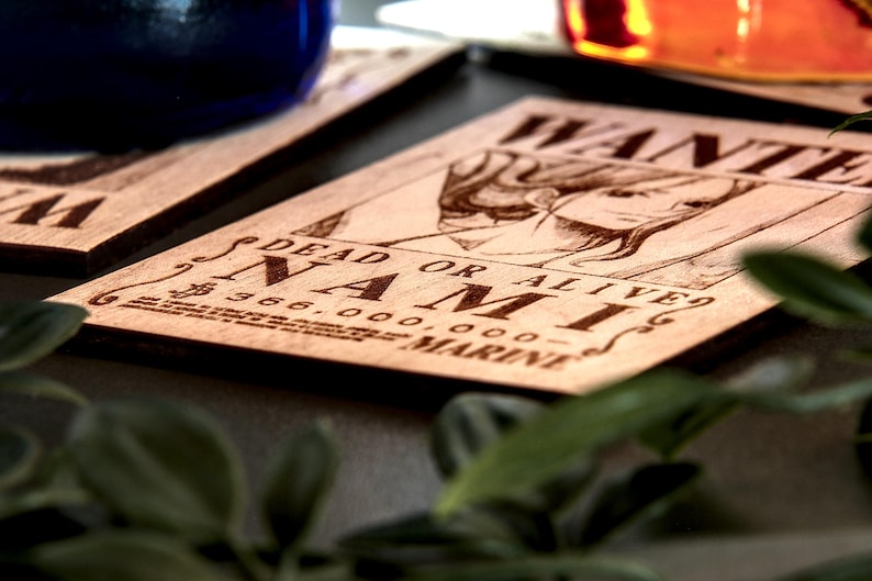 Puede incluir: Posavasos de madera con un dise&ntilde;o grabado con l&aacute;ser de un personaje de la serie de anime One Piece. El posavasos muestra la palabra &laquo;WANTED&raquo; y &laquo;NAMI&raquo; con una cantidad de recompensa. La madera es de color marr&oacute;n claro.
