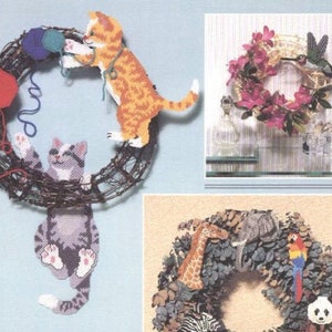 May include: Three different wreaths decorated with various animals and objects. The first wreath is made of twigs and features two cats, one orange and one gray, playing with yarn. The second wreath is made of twigs and features a hummingbird with pink flowers. The third wreath is made of rocks and features a giraffe, an elephant, a parrot, and a panda.