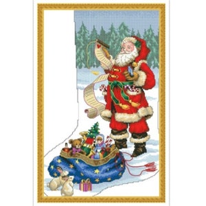 May include: Santa Claus in a red suit with a white beard checks his list while standing next to a large blue and white stocking filled with toys.