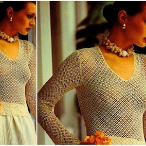 May include: A white crochet top with a v-neck and long sleeves. The top is made of a delicate, open-weave fabric.