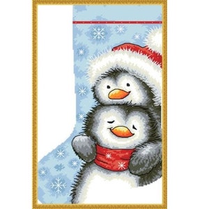 May include: A Christmas stocking with a blue background and snowflakes. Two penguins are inside the stocking, one wearing a Santa hat.