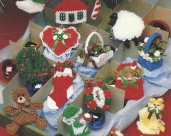 May include: A collection of handmade Christmas ornaments, including a stocking, a heart, a wreath, a basket, a teddy bear, a sheep, and a house. The ornaments are made of yarn and are decorated with beads and other embellishments.