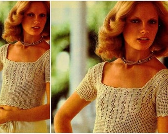 May include: A crocheted top with a square neckline and short sleeves. The top is made of a light beige yarn and has a delicate, lacy pattern.