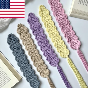 Könnte beinhalten: Sechs handgefertigte Häkel-Lesezeichen in verschiedenen Farben: Blau, Beige, Lila, Gelb und Rosa. Jedes Lesezeichen hat einen gewellten Rand und eine passende Quaste. Die Lesezeichen werden in der Nähe eines offenen Buches präsentiert.