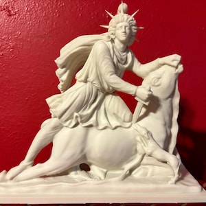 May include: White ceramic statue of a figure riding a bull. The figure is wearing a flowing robe and a crown with spikes. The bull is lying down with its head turned to the side. The statue is on a white base.