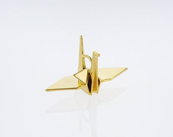May include: A gold origami crane, a traditional Japanese paper folding art form, is shown against a white background.