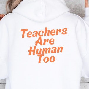 May include: White hooded sweatshirt with the text "Teachers Are Human Too" in orange lettering on the back.