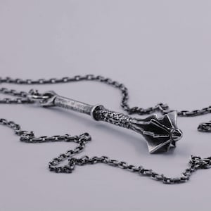 May include: A silver-toned metal pendant shaped like a medieval mace, featuring a textured handle and a flanged head, suspended from a matching silver-toned link chain. The metal has a darkened, oxidized finish that highlights the intricate details.