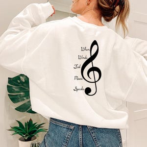 May include: White sweatshirt with a black treble clef graphic and the text "When Words Fail Music Speaks" printed on the back.