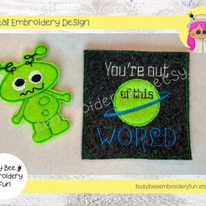 Op de afbeelding: Borduurwerk van een groene alien met een zwart oog en een witte mond. Het ontwerp is op een groene vilt achtergrond. Het tweede ontwerp is een grijze vilt achtergrond met de tekst "You're out of this world" in blauwe borduurgaren. De tekst wordt omringd door een groene planeet met een blauwe ring.