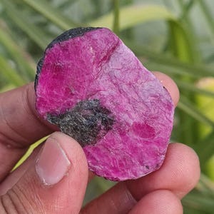 Puede incluir: Una gran gema de rubí rosa sin pulir con inclusiones negras. El rubí es una piedra natural sin pulir.