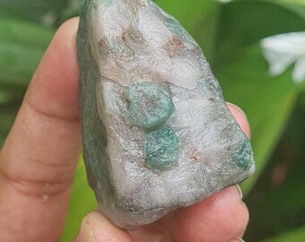 May include: A white and green crystal with a rough, natural texture. The crystal has several green inclusions that are visible on the surface.