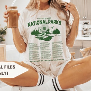 May include: A white t-shirt with a green graphic of a mountain range and the text "UNITED STATES NATIONAL PARKS EST. 1872" and a list of national parks below the graphic. The text "THE HEART OF AMERICA'S WILDLANDS" is at the bottom of the graphic.