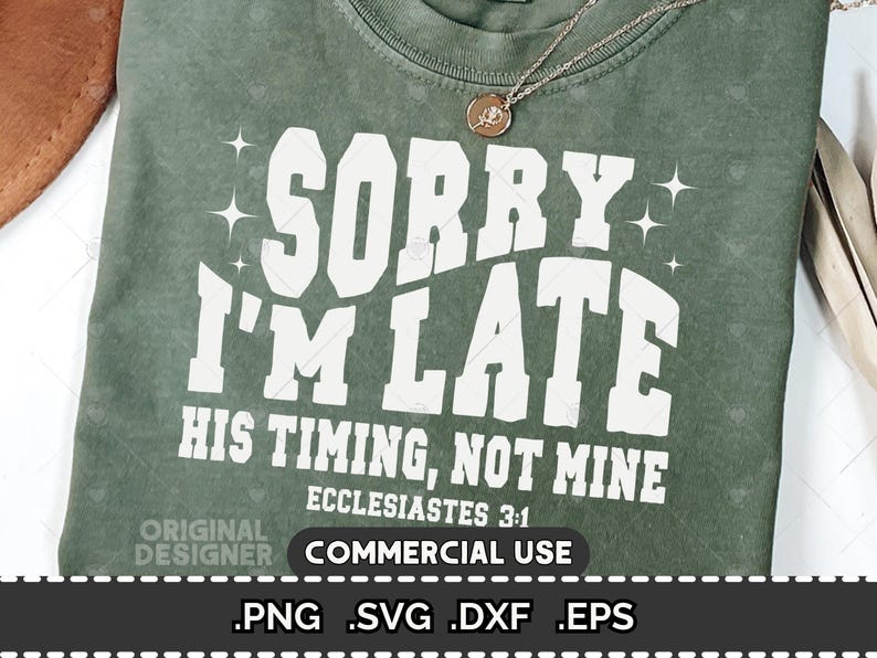 May include: Sage green t-shirt with the text "SORRY I'M LATE" in large white letters. Below, it reads "HIS TIMING, NOT MINE" and "ECCLESIASTES 3:1". A gold necklace with a pendant rests on the shirt. The bottom of the shirt has the words "COMMERCIAL USE".