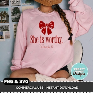 May include: Pink sweatshirt with a red bow and the text "She is worthy. Proverbs 31" printed on the front.