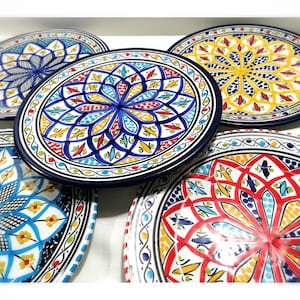 May include: A collection of decorative ceramic plates with intricate, colorful floral designs. Each plate features a unique pattern in shades of blue, yellow, red, and green, with a dark blue border. The plates are round and appear to be hand-painted.