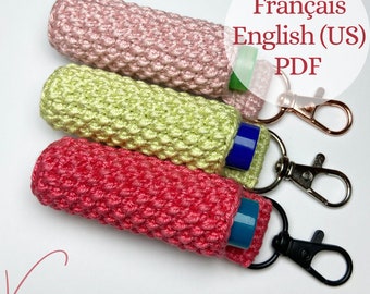 Puede incluir: Tres porta-bálsamos labiales de crochet en rosa, verde y rojo con un llavero plateado. Los porta-bálsamos labiales están hechos con un punto texturizado. El texto "Français English (US) PDF" es visible en la imagen.