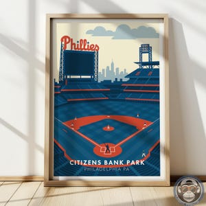 May include: A framed art print of Citizens Bank Park, home of the Philadelphia Phillies. The print features a stylized illustration of the baseball stadium in shades of blue, orange, and beige, with the word "Phillies" at the top.