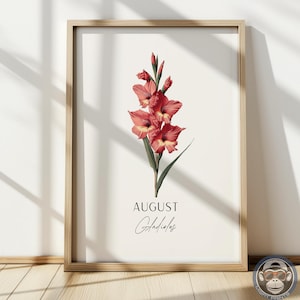 Könnte beinhalten: Gerahmter Kunstdruck mit einer botanischen Illustration einer roten Gladiolenblume. Der Druck enthält das Wort "AUGUST" und den Namen der Blume, "Gladiolus", in eleganter Schrift. Das Kunstwerk ist vor einem cremefarbenen Hintergrund.