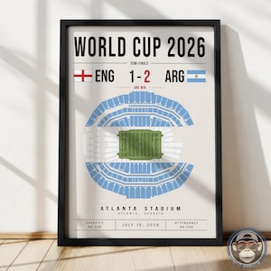 May include: A framed poster titled WORLD CUP 2026 showing a semi-final match between England and Argentina with a score of 1-2. The print features a top-down stadium diagram, the location Atlanta Stadium, Georgia, and the date July 15, 2026.