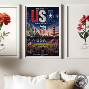 May include: Three framed wall art prints. The left shows an orange marigold flower with the text OCTOBER Marigold. The center features a World Cup 2026 USA poster with the Statue of Liberty, Golden Gate Bridge, and a stadium. The right shows a pink sweet pea flower with the text APRIL Sweet Pea.