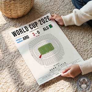 May include: A white commemorative poster for the World Cup 2026 featuring the text World Cup 2026, a 3-0 score for Argentina against Algeria, a stadium diagram with a highlighted red section, and details for Geha Field in Kansas City, Missouri.