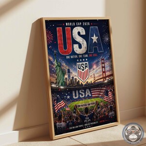 May include: A framed vertical poster for World Cup 2026 featuring the text USA in large red, white, and blue letters. The design includes the Statue of Liberty, the Golden Gate Bridge, a soccer stadium, the USA soccer crest, and American flags.