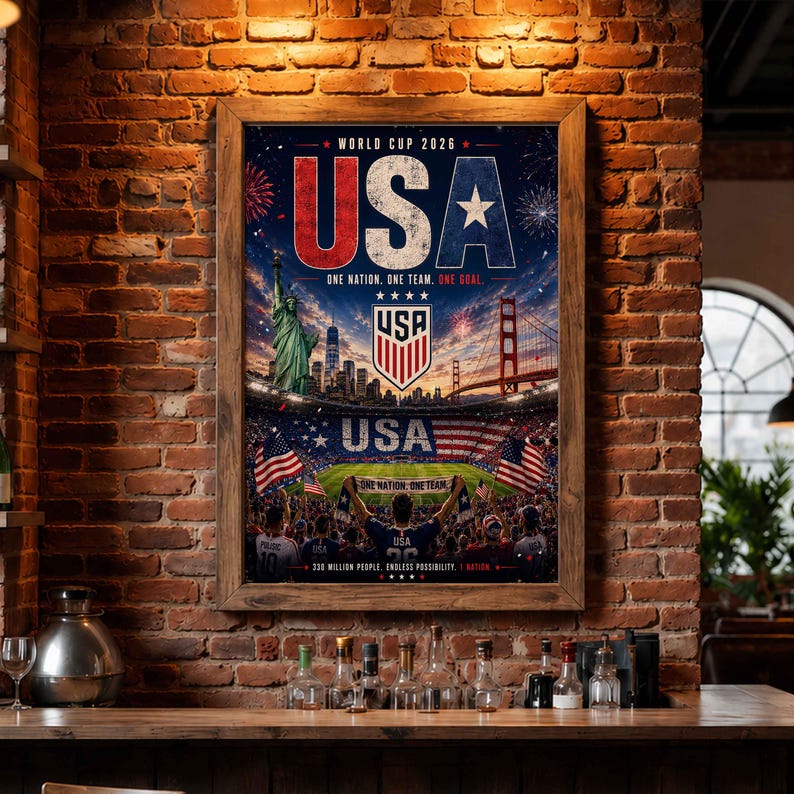 May include: A framed poster titled World Cup 2026 USA featuring the Statue of Liberty, the Golden Gate Bridge, a soccer stadium, and the text One Nation. One Team. One Goal. The design includes American flags and a soccer crest on a dark background.