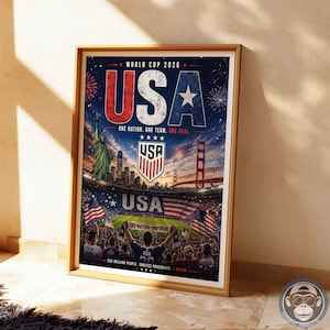 May include: A framed poster for the World Cup 2026 featuring the text USA, the Statue of Liberty, the Golden Gate Bridge, a soccer stadium, American flags, and the phrase One Nation. One Team. One Goal. The design includes fireworks and a crowd.