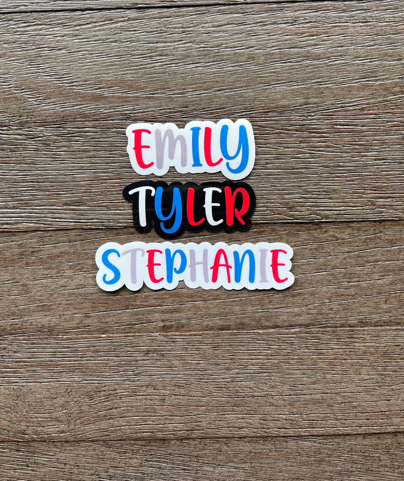 May include: Three personalized name stickers with white backgrounds and colorful lettering. The names are "Emily", "Tyler", and "Stephanie".