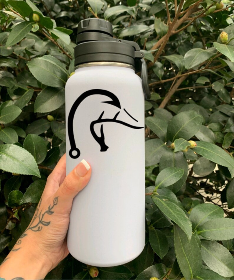 K&ouml;nnte beinhalten: Wei&szlig;e Wasserflasche mit einem schwarzen Enten- und Geweihdesign. Die Flasche hat einen schwarzen Deckel mit einer Schlaufe.