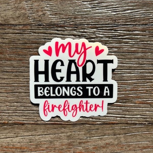 K&ouml;nnte beinhalten: Wei&szlig;er Aufkleber mit schwarzem Text, der "my heart belongs to a firefighter!" lautet, mit zwei rosa Herzen &uuml;ber dem Wort "my".