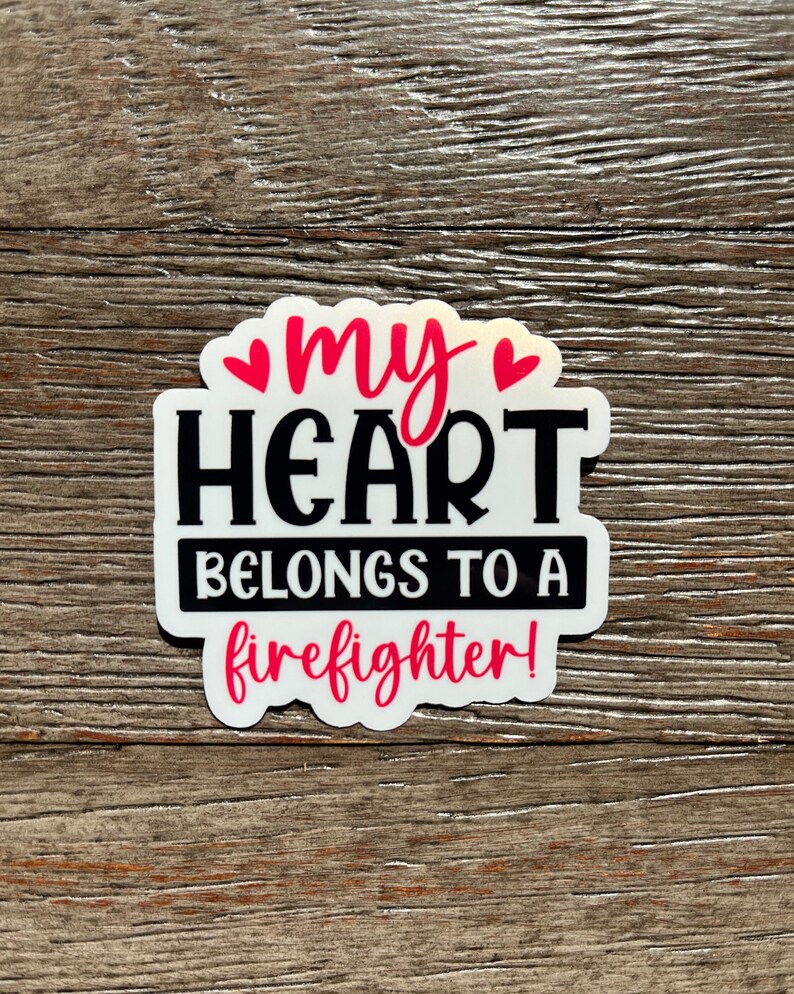 K&ouml;nnte beinhalten: Wei&szlig;er Aufkleber mit schwarzem Text, der "my heart belongs to a firefighter!" lautet, mit zwei rosa Herzen &uuml;ber dem Wort "my".