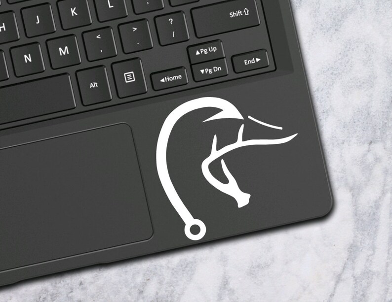 K&ouml;nnte beinhalten: Wei&szlig;er Vinyl-Aufkleber mit einem Hirschgeweih, an dessen Ende ein Angelhaken befestigt ist. Der Aufkleber befindet sich auf einem schwarzen Laptop.