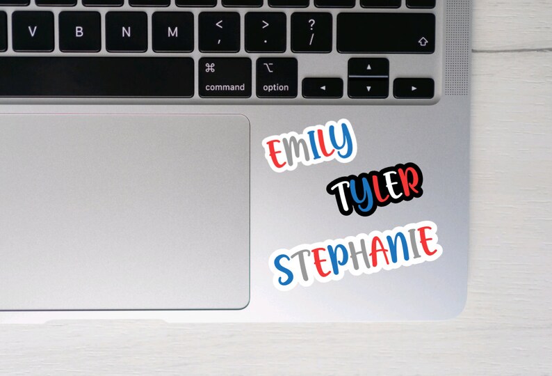 May include: Three colorful name stickers on a silver laptop. The names are "Emily", "Tyler", and "Stephanie".