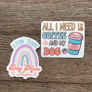 K&ouml;nnte beinhalten: Zwei Aufkleber mit Hunde-Motiven. Der erste Aufkleber zeigt einen Regenbogen mit Pfotenabdr&uuml;cken und den Text "Livin' That Dog Mom Life". Der zweite Aufkleber zeigt eine Kaffeetasse mit einem Pfotenabdruck und den Text "All I Need Is Coffee And My Dog".