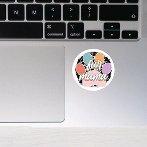 K&ouml;nnte beinhalten: Ein runder Aufkleber mit einem Pfotenabdruck-Design in Schwarz, Wei&szlig; und Pastellfarben. Der Pfotenabdruck hat die Worte "fur mama" darin geschrieben.