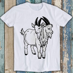 May include: A white short-sleeved t-shirt featuring a black ink-style graphic illustration of a two-headed goat. The goat is depicted in profile with detailed horns, shaggy fur, and hooves, centred on the front of the garment.