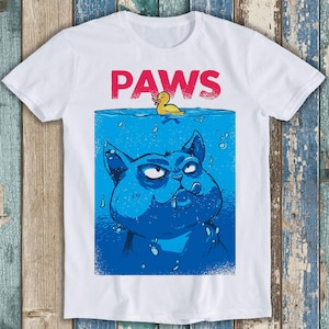 May include: White t-shirt with a blue cat and a yellow rubber ducky in a blue pool. The text "PAWS" is printed in red above the cat.