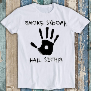Op de afbeelding: Wit T-shirt met zwarte tekst en een handafdruk-afbeelding. De tekst luidt "Smoke Skooma Hail Sithis".